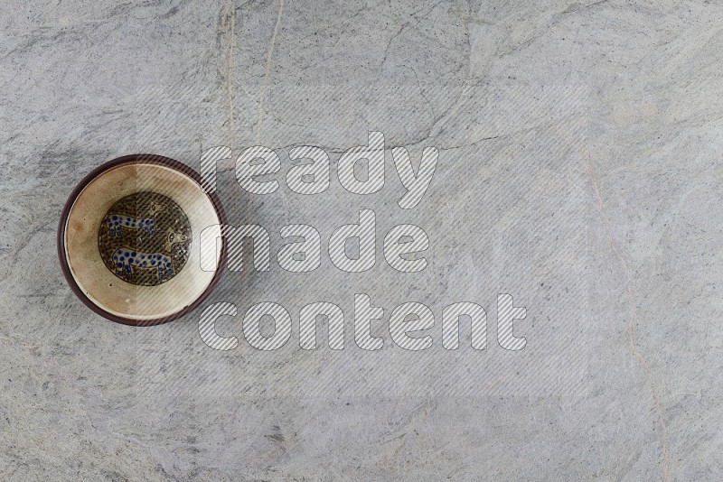 Top View Shot Of A Decorative Pottery Plate On Grey Marble Flooring