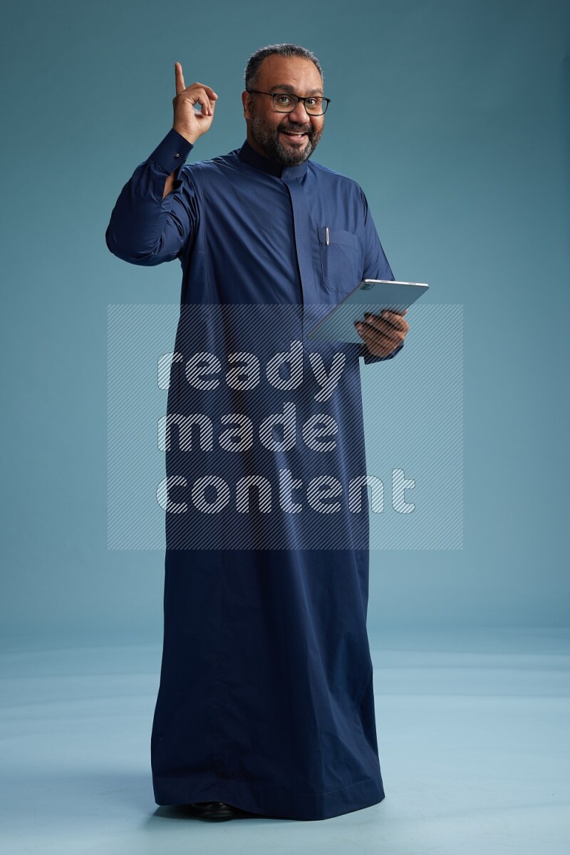 Saudi Man without shimag Standing working on tablet on blue background