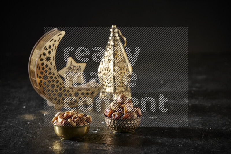 Dates in a metal bowl with mixed nuts beside golden lanterns in a dark setup
