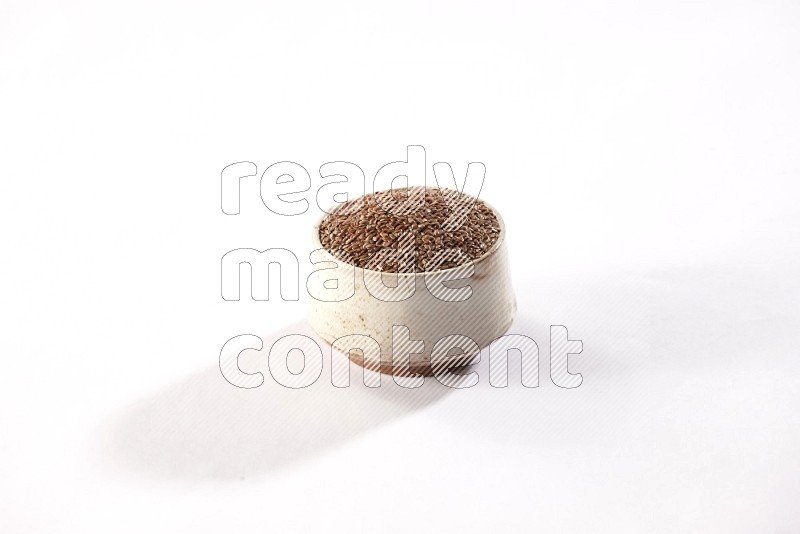 وعاء بيج فخاري ممتلئ بحبوب بذر الكتان علي خلفية بيضاء