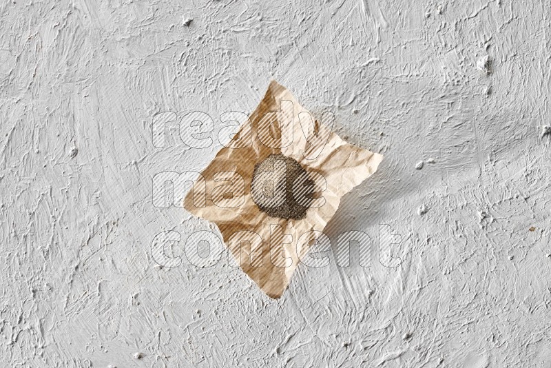 Black pepper powder on a crumpled paper on a textured white flooring