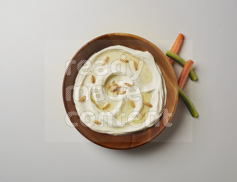 Lebnah garnished with pine nuts in a wooden plate on a white background