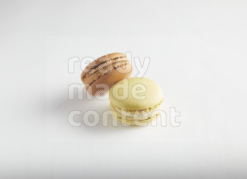 45º Shot of of two assorted Brown Irish Cream, and Yellow Lime macarons on white background