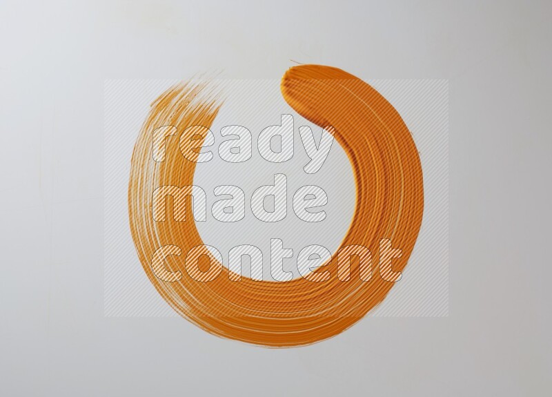 An orange circular painting brush stroke on white background