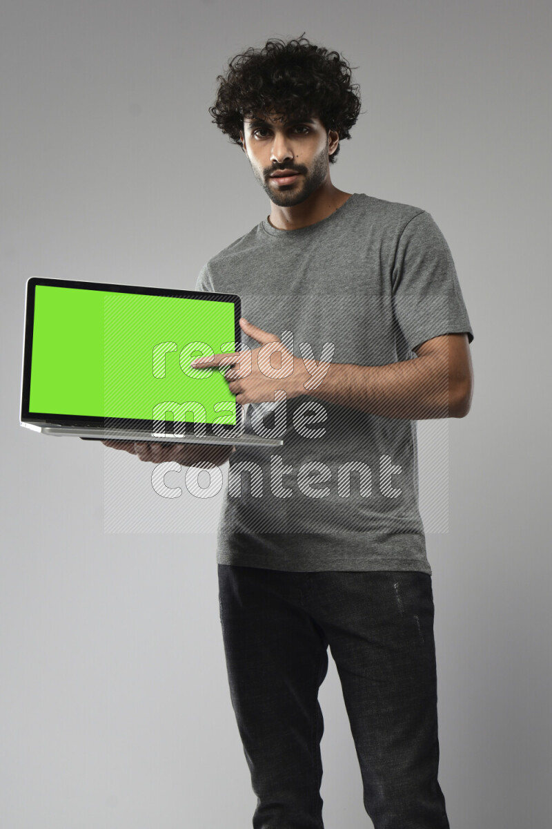 A man wearing casual standing and showing a laptop screen on white background