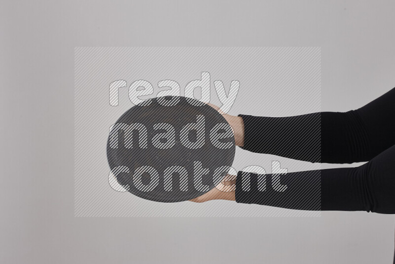 A woman in black abaya holding different pottery essentials in different positions