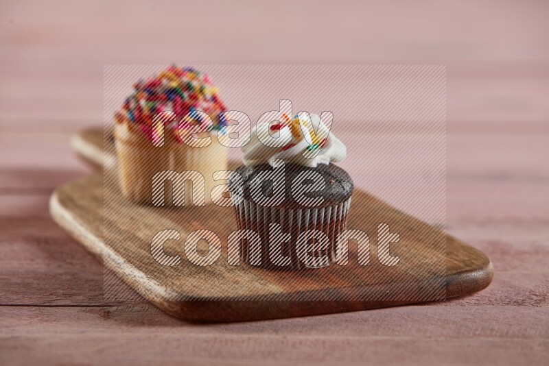 Chocolate mini cupcake topped with cream on a wooden board