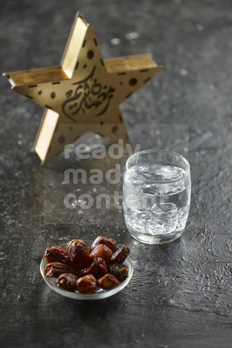 A wooden golden star lantern with different drinks, dates, nuts, prayer beads and quran on textured black background