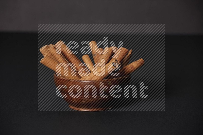 Cinnamon Sticks in a wooden bowl on black background