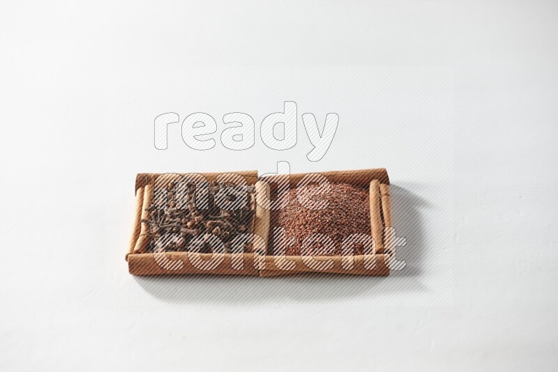 مربعان من أعواد القرفة ممتلئان بحب الرشاد والقرنفل علي خلفية بيضاء