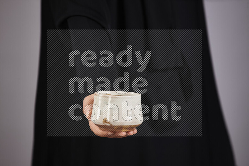 A woman in black abaya holding different pottery essentials in different positions
