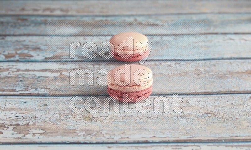 45º Shot of two Pink Litchi Raspberry macarons on light blue wooden background