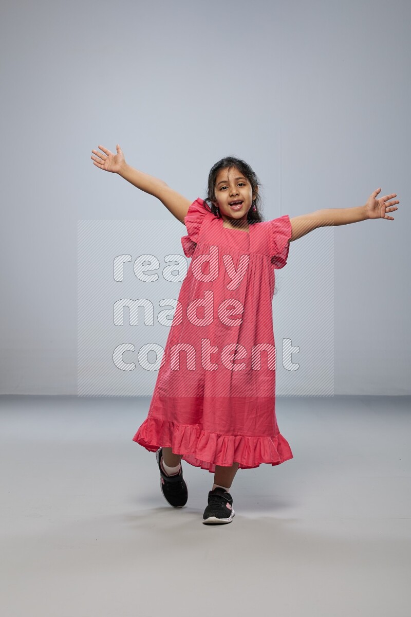 A girl standing interacting with the camera on gray background
