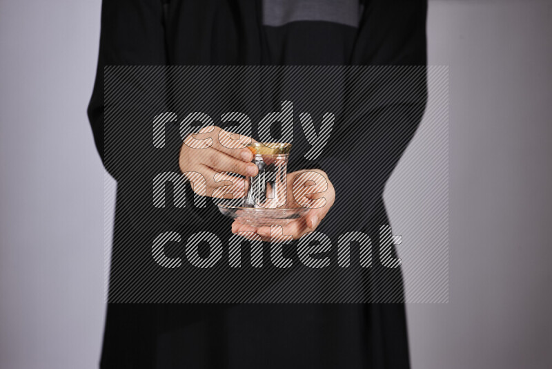 A woman in black abaya holding different glassware in different positions