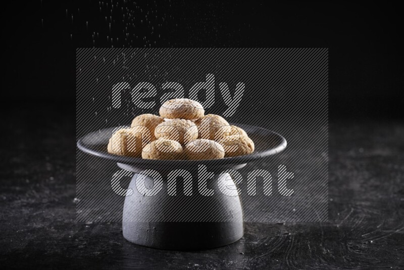 Kahk on a serving plate on a black background