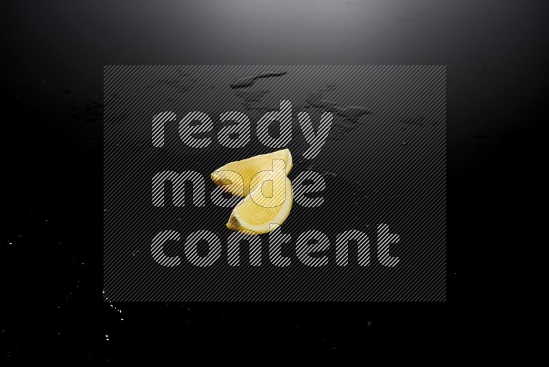 Lemon wedges with water drops, and droplets on black background