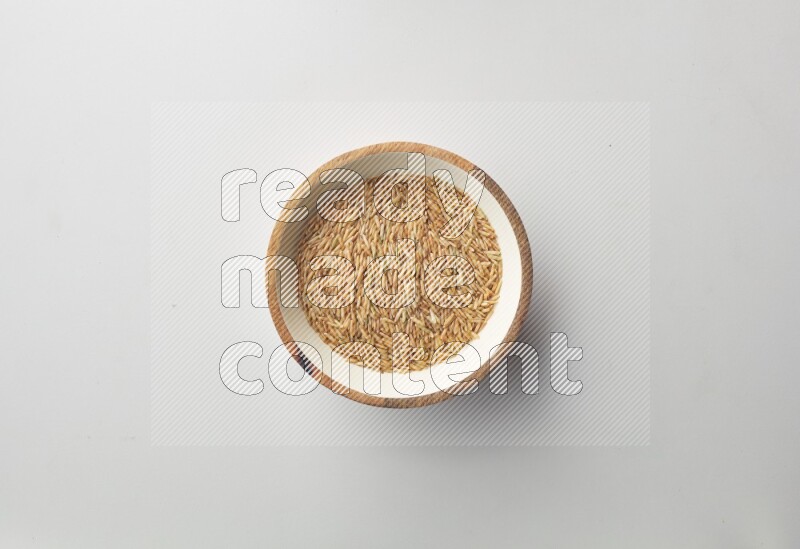 Top-view shot of long grain brown rice in a container on white background