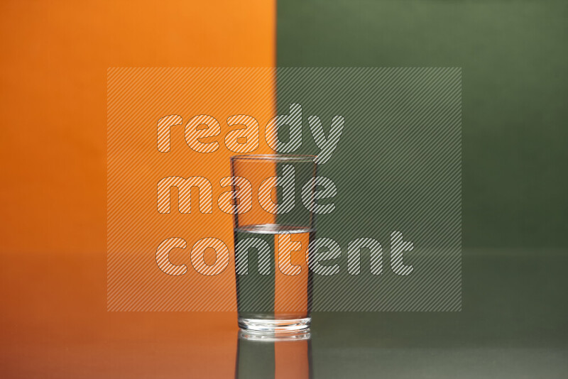 The image features a clear glassware filled with water, set against orange and dark green background