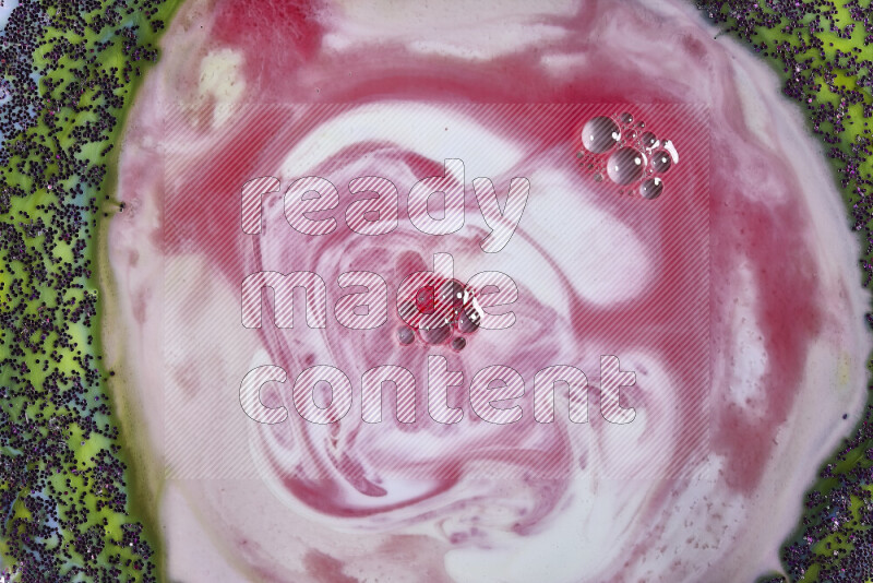 A close-up of swirls of red and white with sparkling purple glitter scattered on green and blue background