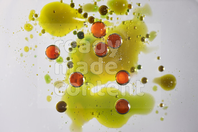 لقطات مقربة لقطرات ألوان مائية حمراء وخضراء وصفراء على سطح الزيت على خلفية بيضاء