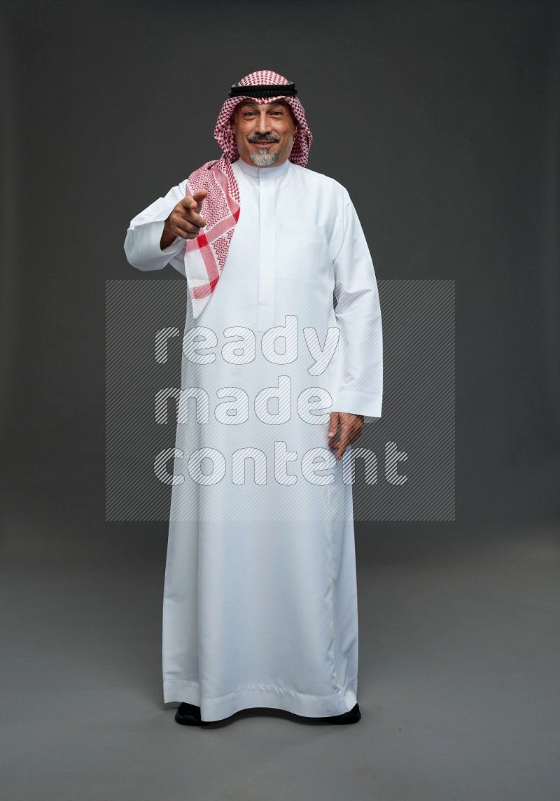 Saudi man with shomag Standing Interacting with the camera on gray background