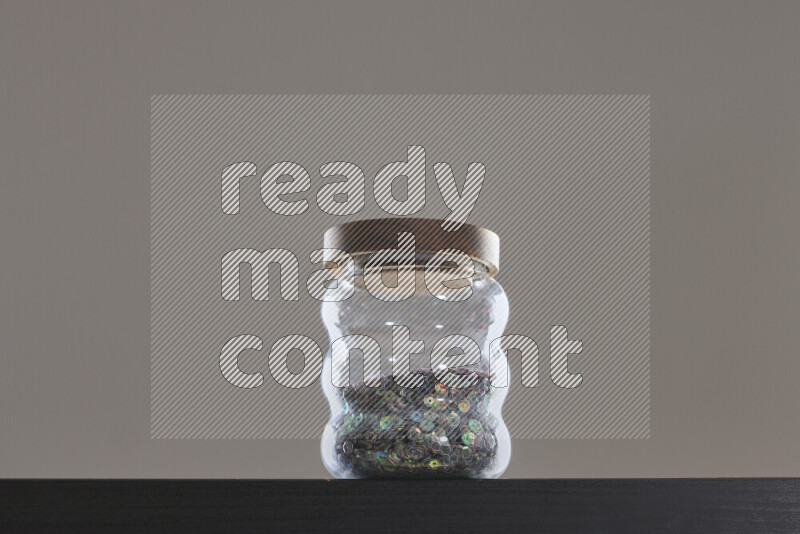 Sequins in a glass jar on black background