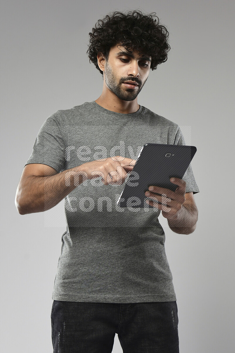 A man wearing casual standing and browsing on a tablet on white background