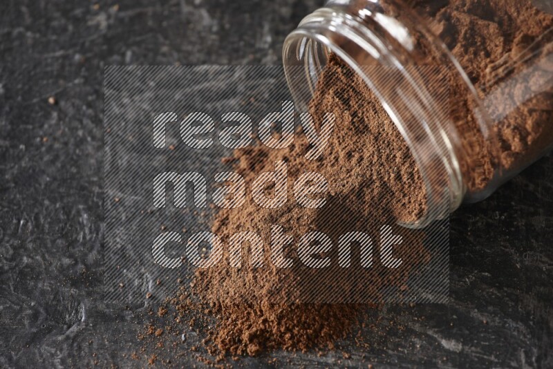 وعاء زجاجي مقلوب ممتلئ ببودرة القرنفل على أرضية سوداء