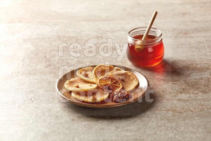 Five stacked dried orange mini pancakes in a brown plate on beige background