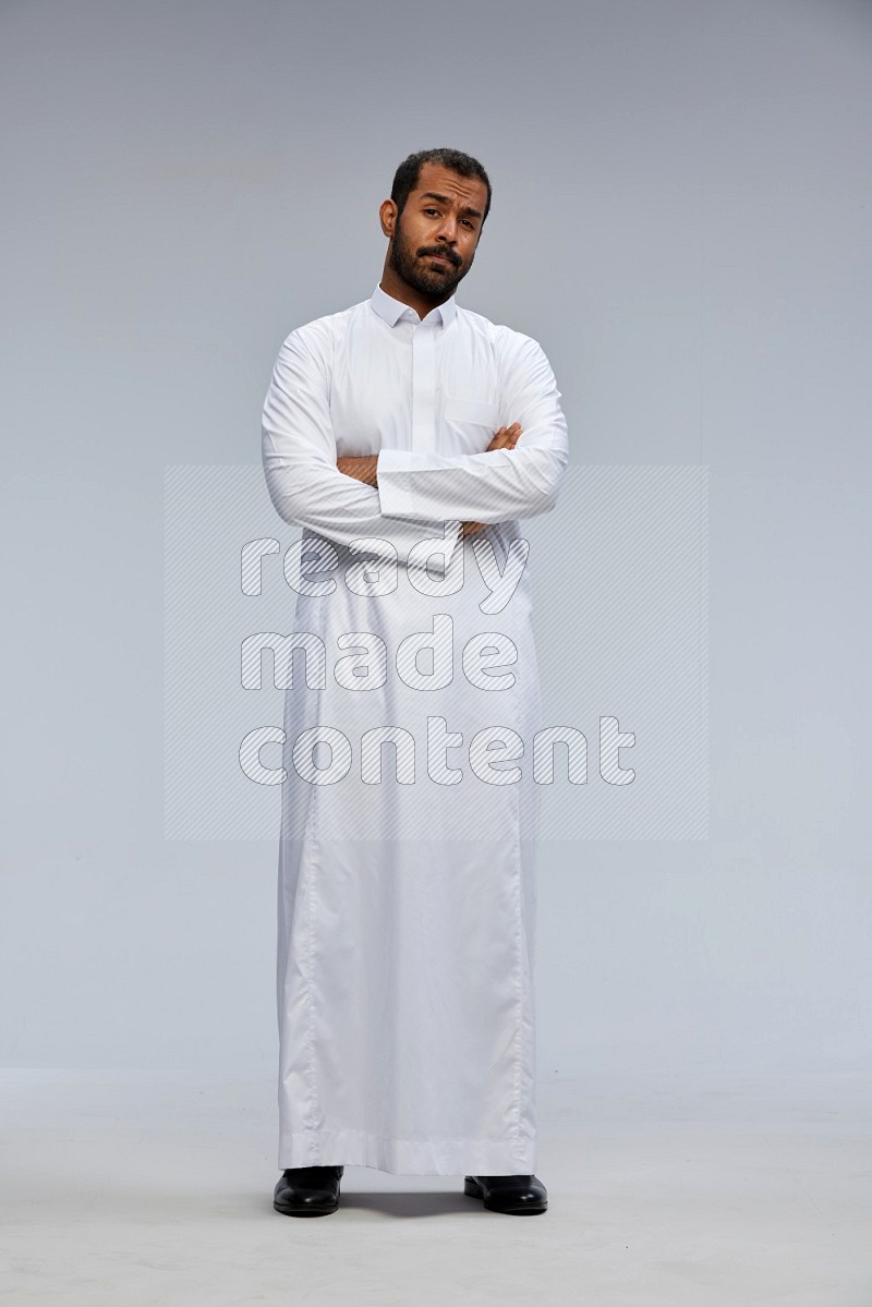 Saudi man wearing Thob standing with crossed arms on Gray background