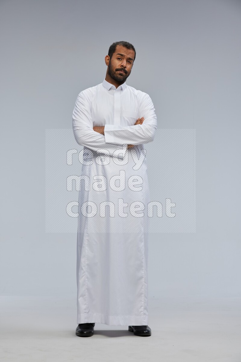 Saudi man wearing Thob standing with crossed arms on Gray background