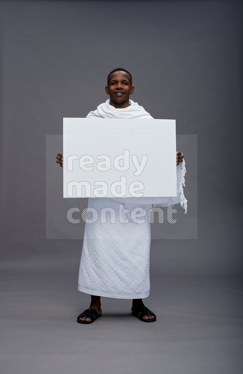 A man wearing Ehram Standing holding board sign on gray background