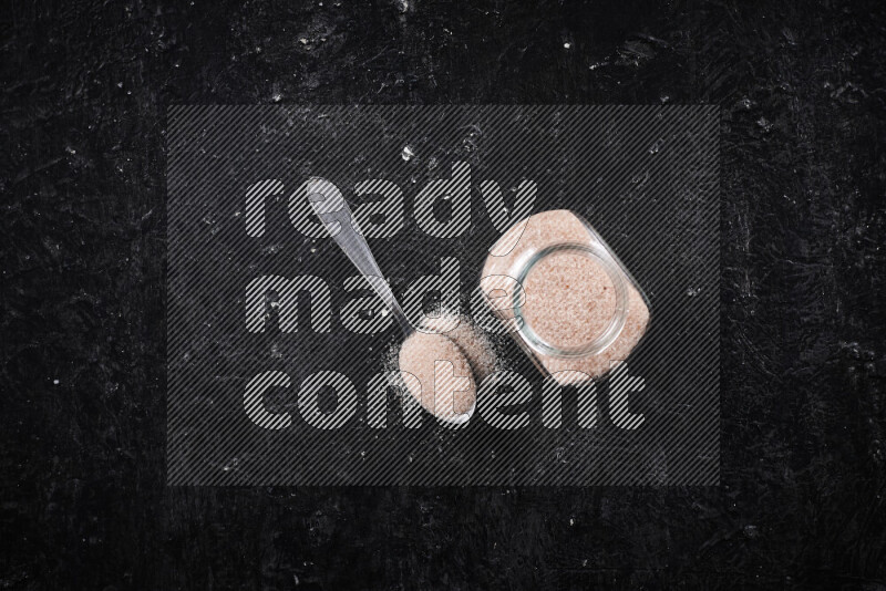 وعاء زجاجي ممتلئ بملح الهيمالايا الناعم على خلفية سوداء