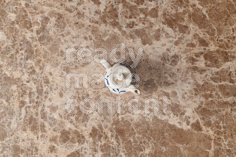 A pottery teapot on beige marble background