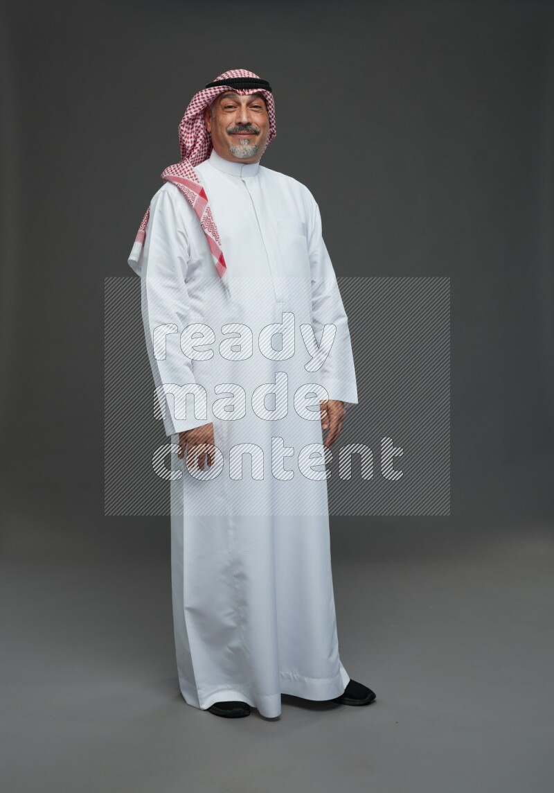 Saudi man with shomag Standing Interacting with the camera on gray background