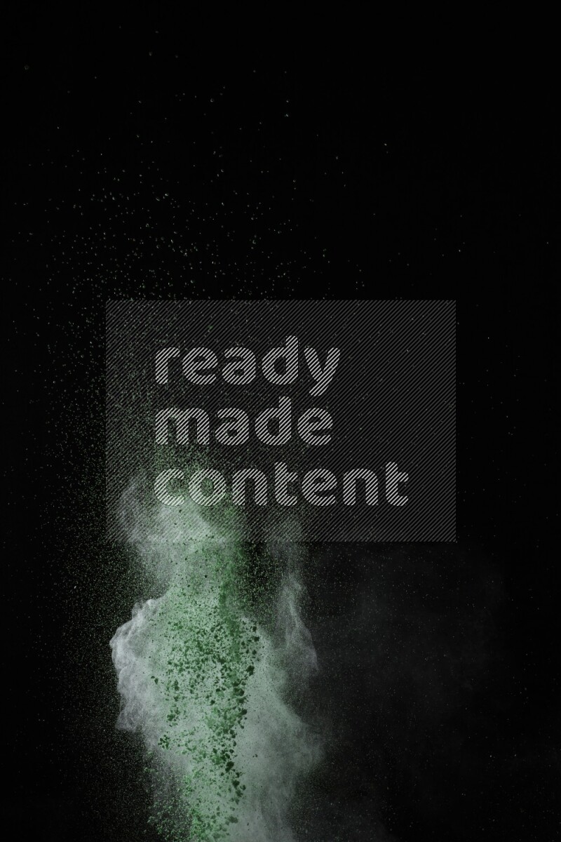 A side view of green powder explosion on black background