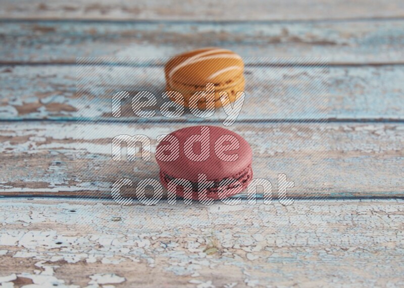 45º Shot of of two assorted Brown Irish Cream, and Red Cherry macarons  on light blue background