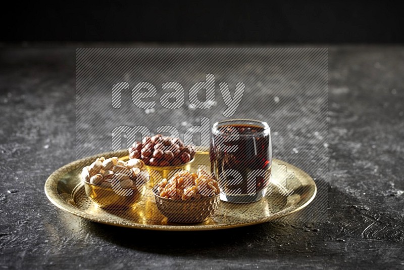 Nuts in metal bowls with tamarind on a tray in dark setup