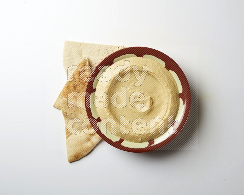 Plain hummus in a traditional plate on a white background