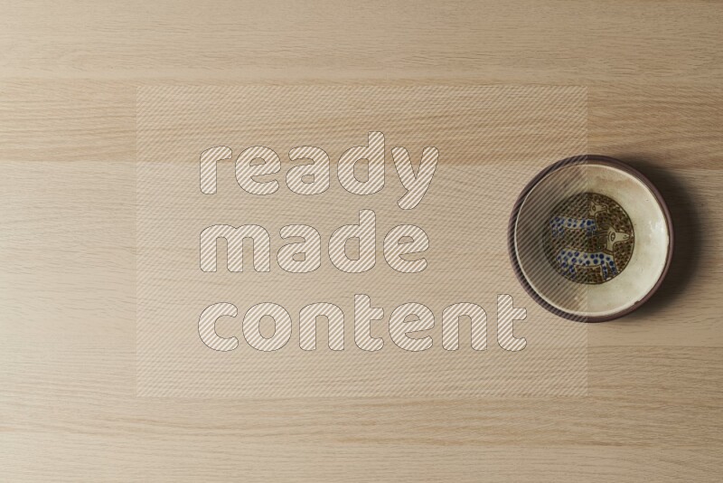 صحن فخاري مزخرف على خلفية خشبية فاتحة