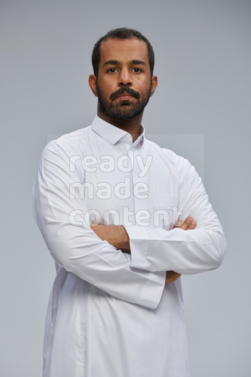 Saudi man wearing Thob standing with crossed arms on Gray background