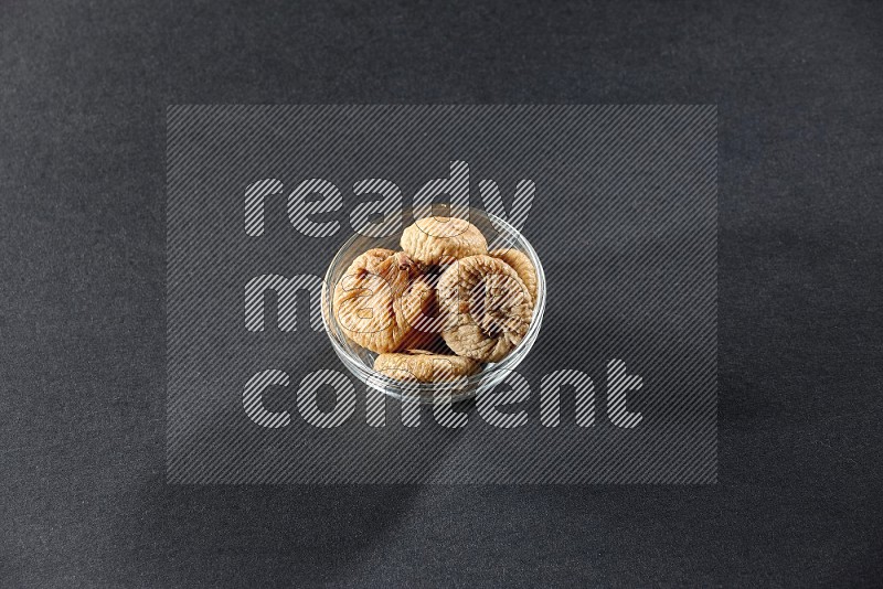 A glass bowl full of dried figs on a black background in different angles