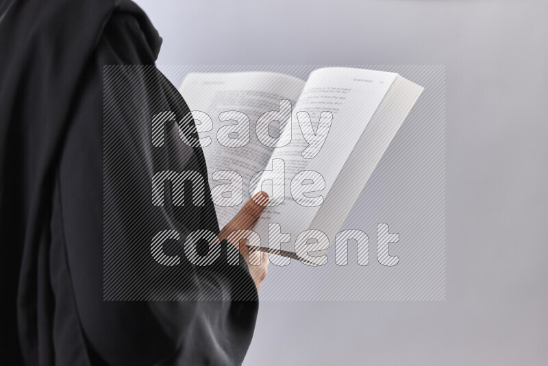 A woman in abaya holding books and a board in different positions (back to school)