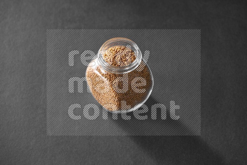 حبوب الخردل في وعاء زجاجي علي خلفية سوداء