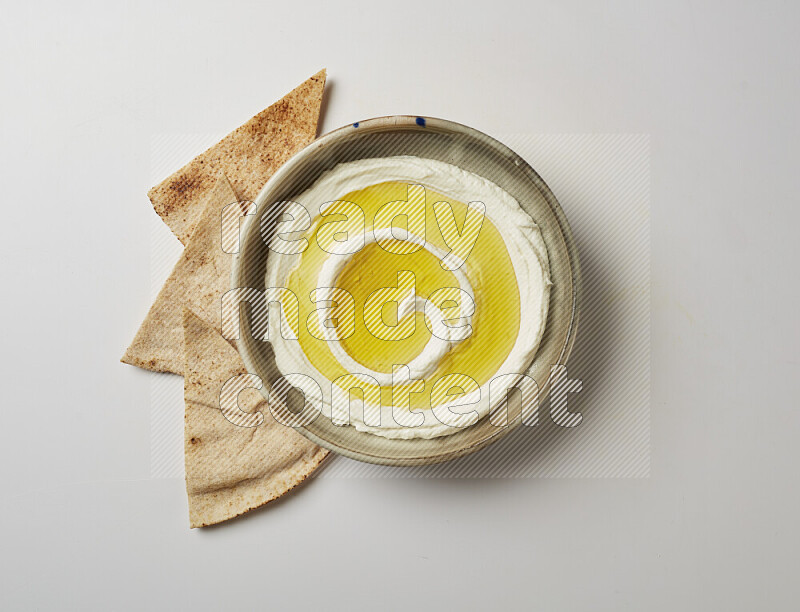 Lebnah garnished with olive oil in a grey pottery plate on a white background