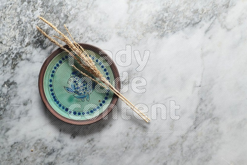 Wheat stalks on Decorative Pottery Plate on grey marble flooring, Top view