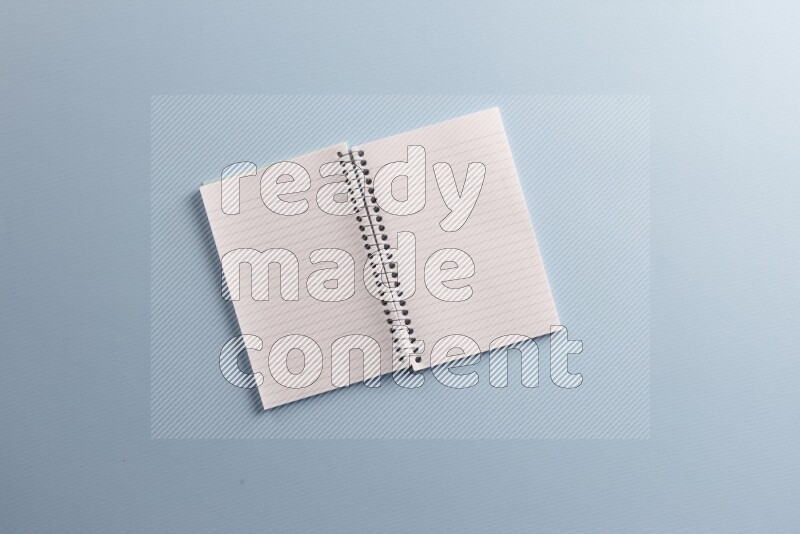 A blank open notebook with different school supplies on blue background