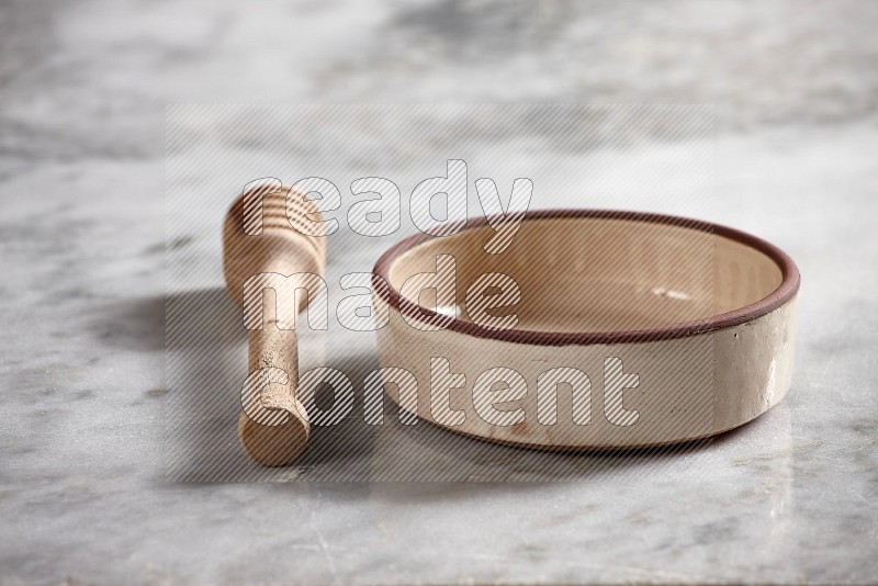 Beige Pottery Oven Bowl with wooden honey handle on the side with grey marble flooring, 15 degree angle