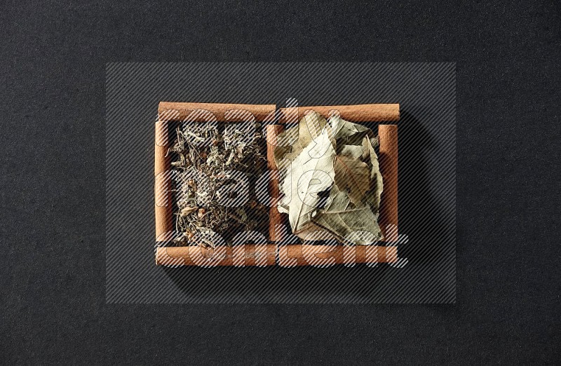 2 squares of cinnamon sticks full of bay laurel leaves and dried basil on black flooring