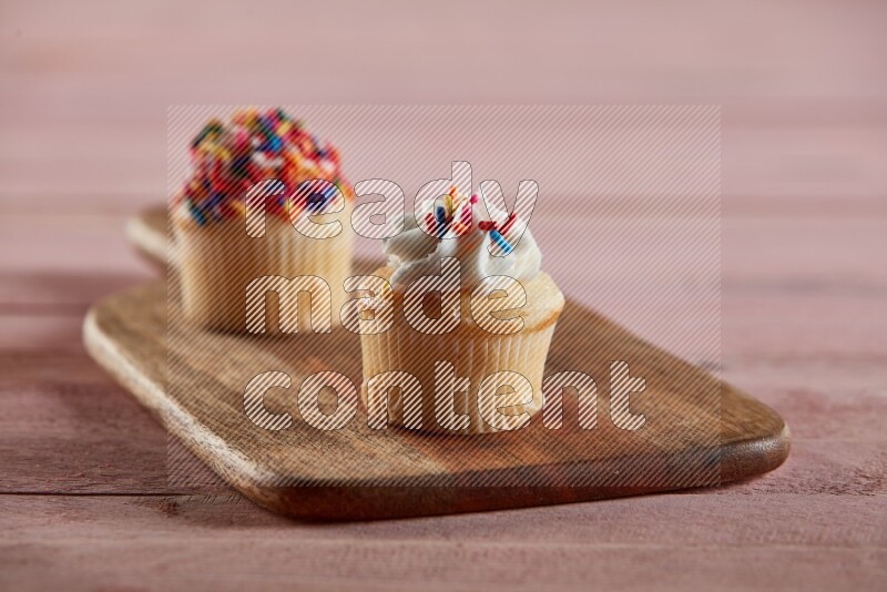 Vanilla mini cupcake topped with cream on a wooden board